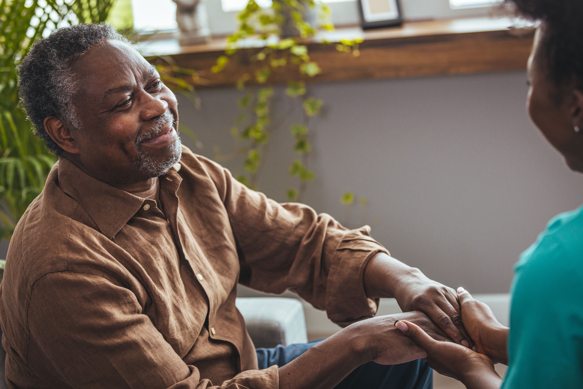 Female carer holding hands of senior man